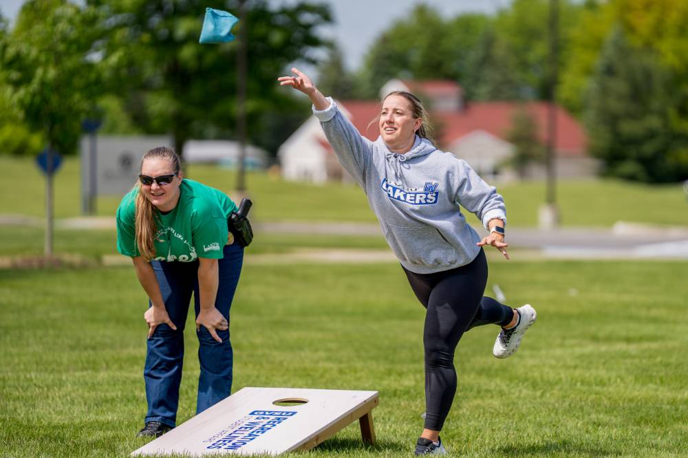 A players throws a bag while a member of the other team looks on